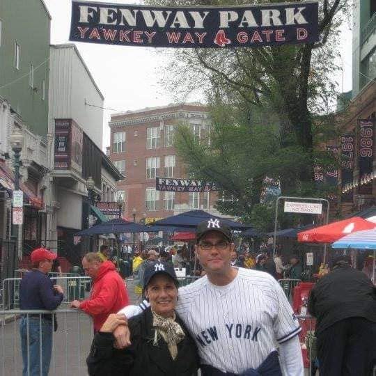 Matthew S Crawford and his mother in Yankees gear beneath the Fenway Park Yawkey Way Gate D sign in Boston