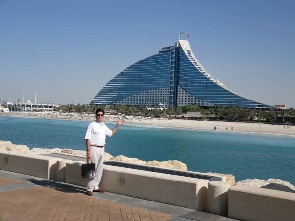 Matthew on the walkway, waving toward the Jumeirah Beach Hotel across the water