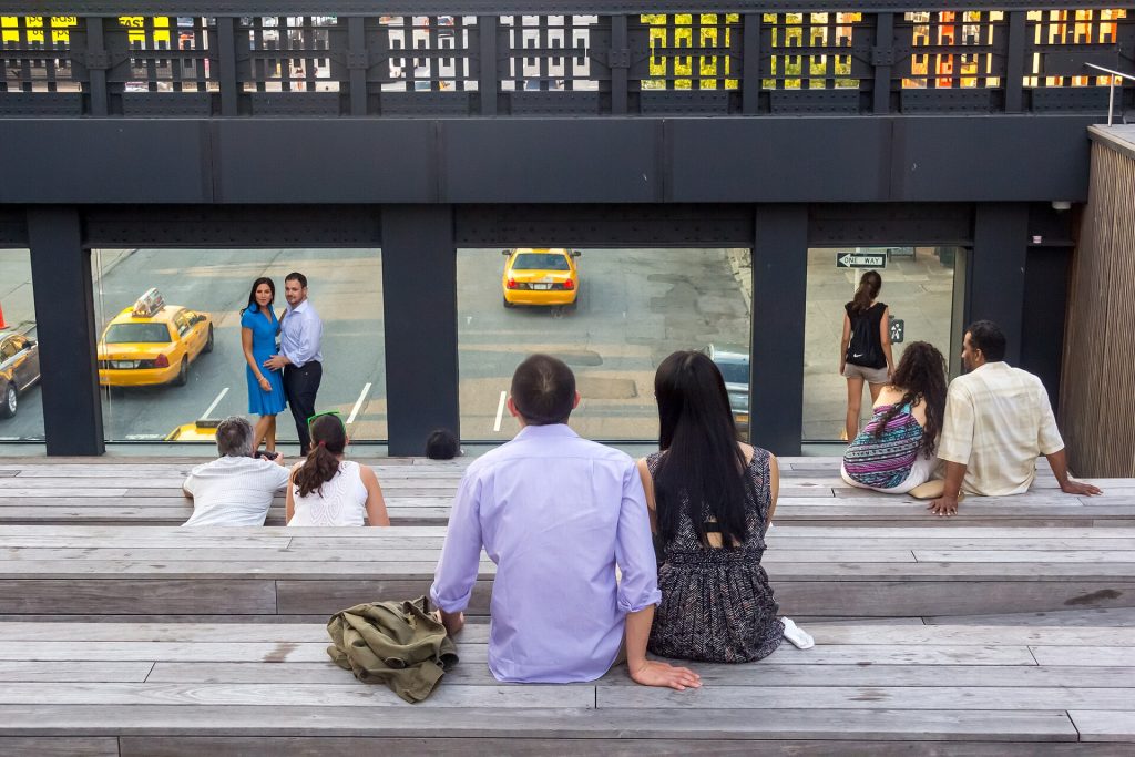 People sitting on the wooden steps of the High Line above a Chelsea street