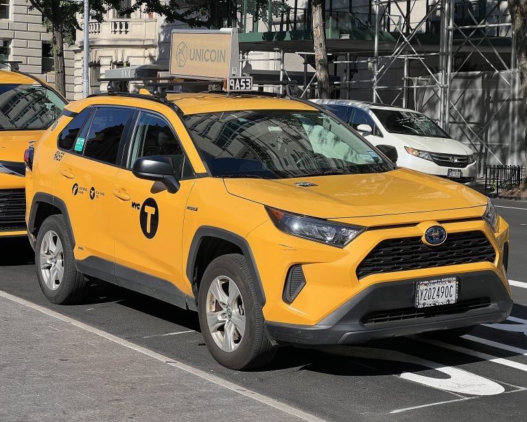 Yellow NYC taxicab driving through Midtown Manhattan