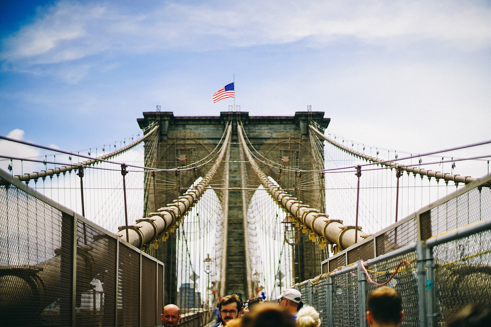 Pedestrians walking across the elevated wooden promenade of the Brooklyn Bridge