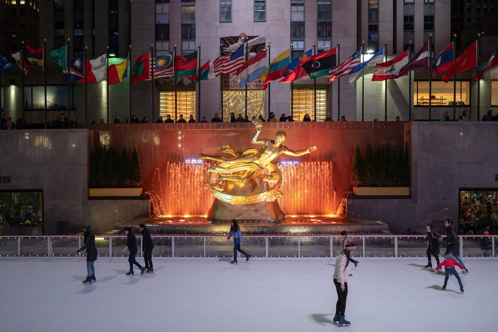 Skaters on the ice rink at Rockefeller Center below the golden Prometheus statue