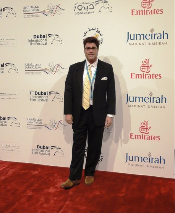 Matthew in a dark suit and yellow tie on the red carpet