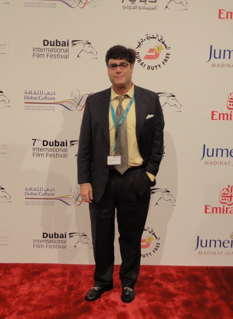 Matthew in a pinstripe suit with a festival pass on the red carpet