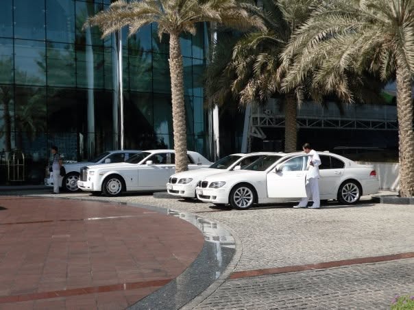 A row of white Rolls-Royce Phantoms in the hotel driveway