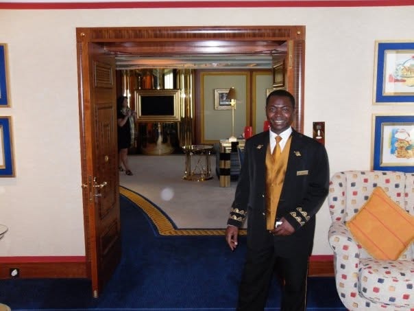 The suite's butler in a black and gold uniform at the doorway