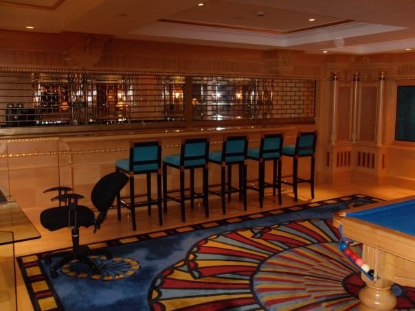 The suite's private bar with blue bar stools and wood paneling