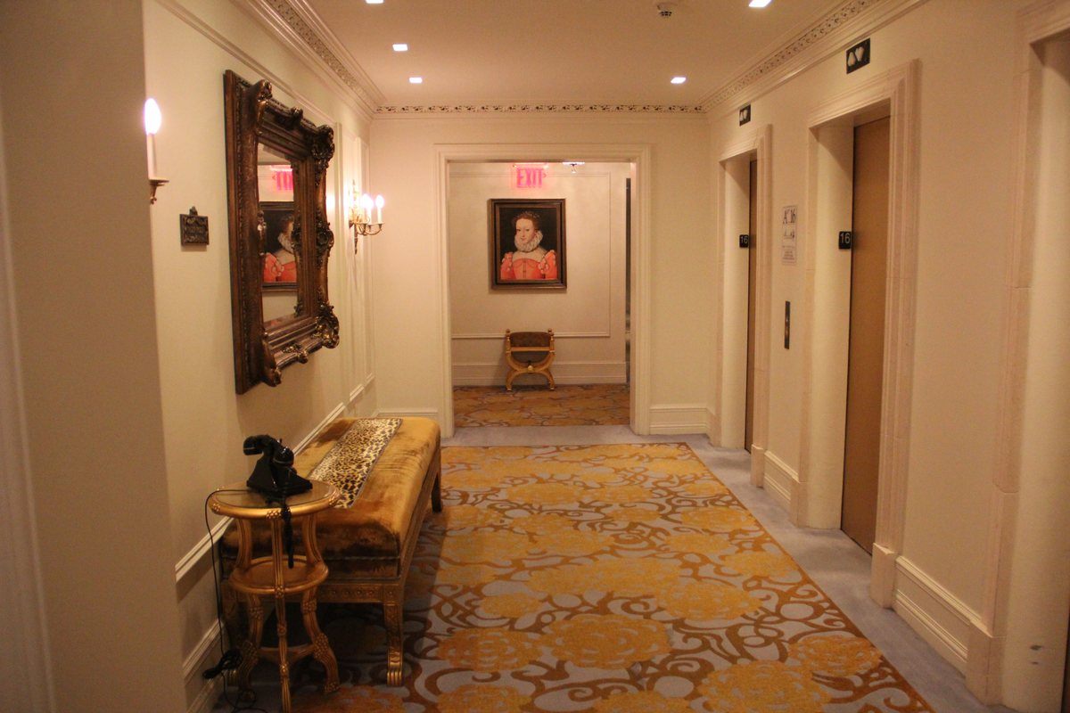 The Plaza elevator landing on the 16th floor with gold carpet, candle sconces and a vintage phone