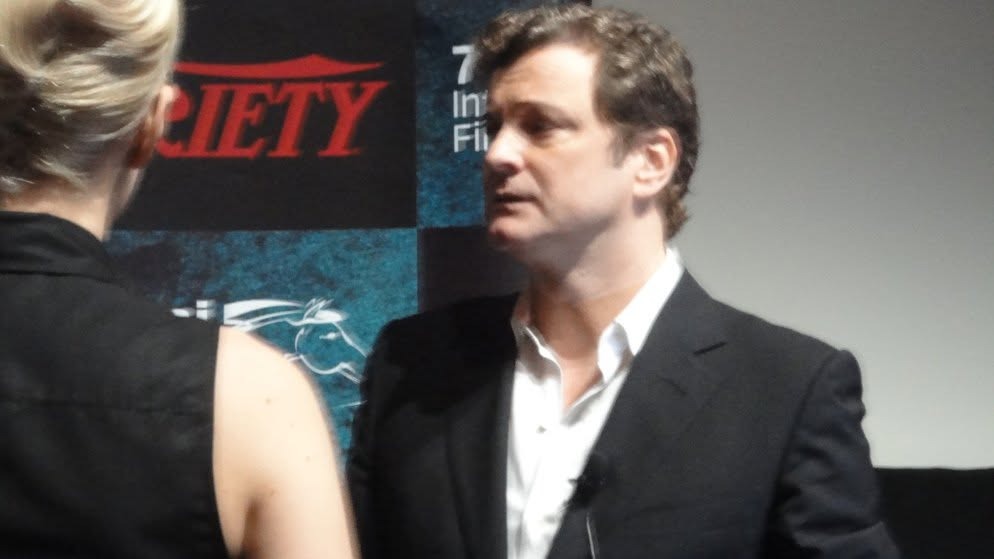 Colin Firth in a dark jacket in front of the Variety backdrop